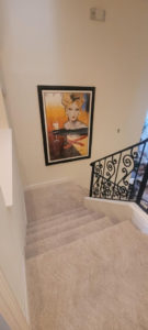 wall to wall carpet in stairway with painting on the wall