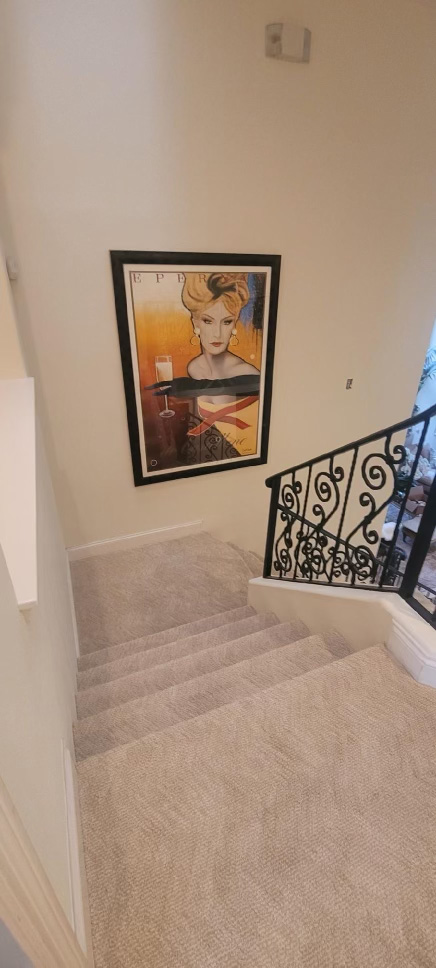 wall to wall carpet in stairway with painting on the wall