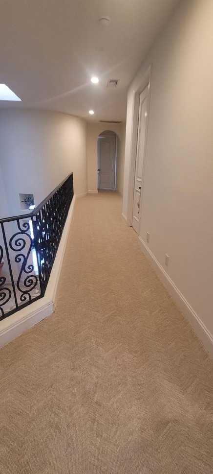 wall to wall carpet in hallway with metal stair rail